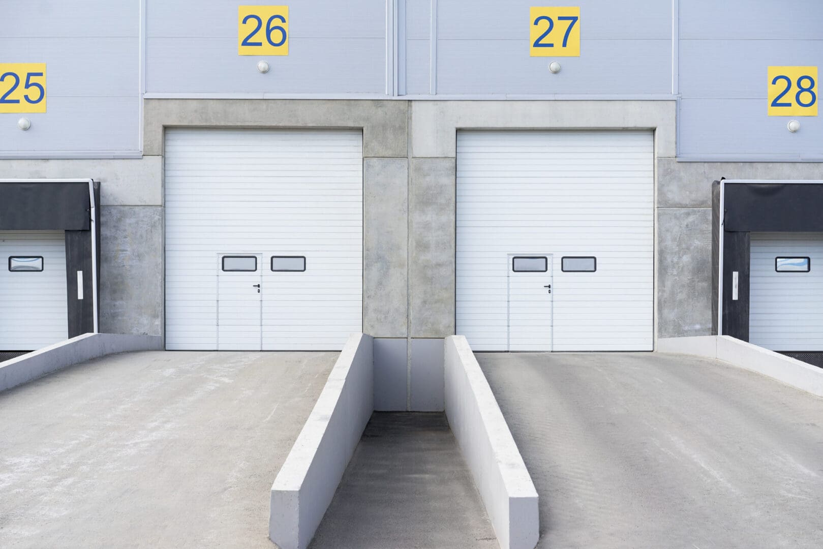 Two white doors in a building with numbers on the side.