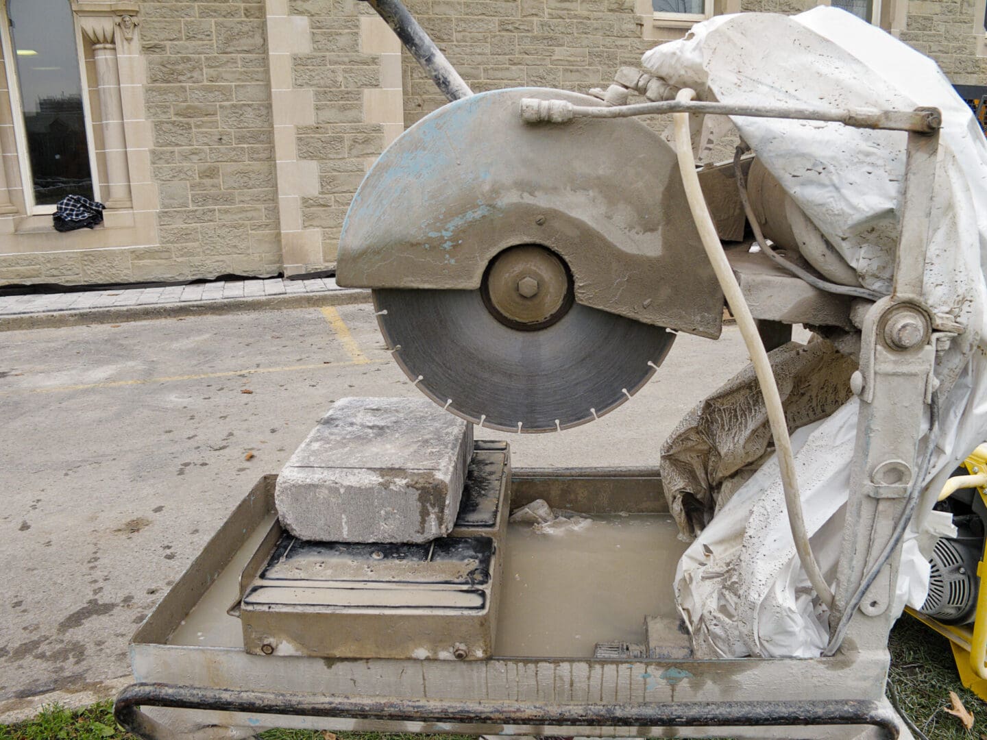 A circular saw cutting through concrete on the side of a road.