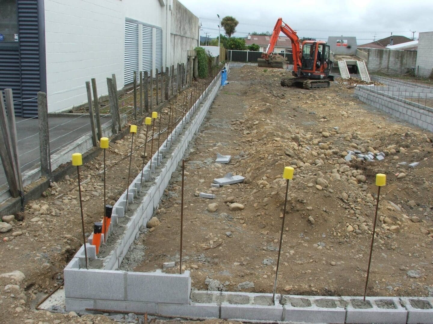A construction site with a red tractor and yellow poles.