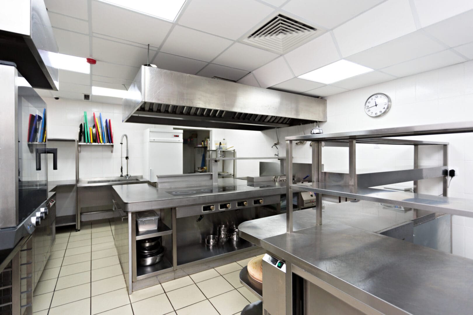 A kitchen with stainless steel counters and a clock.