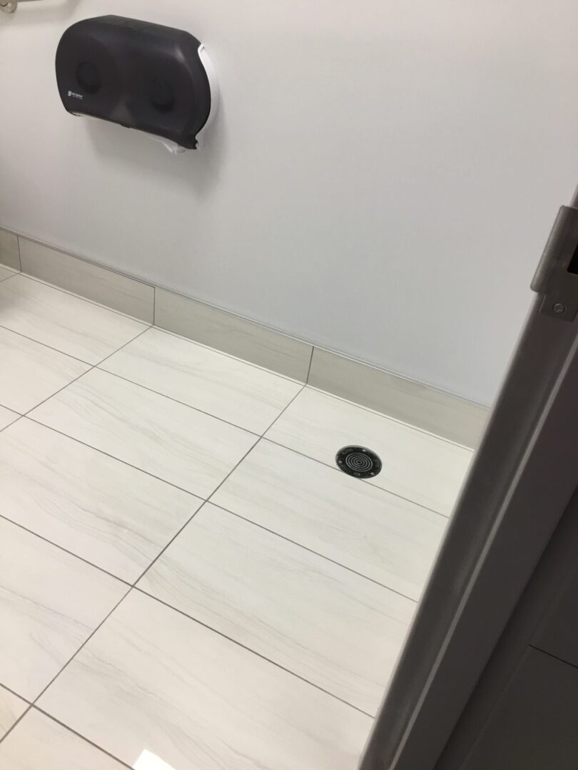 A bathroom with white tile and a black floor.