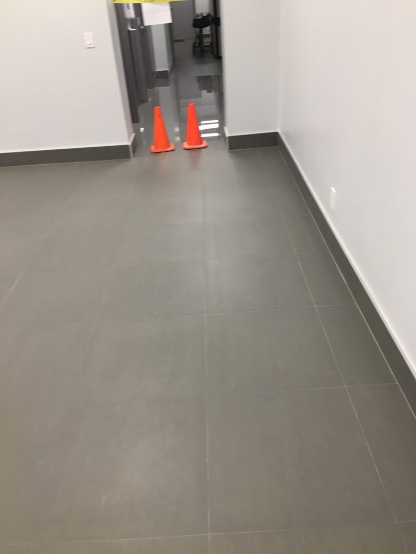 Two orange cones in a room with grey floors.