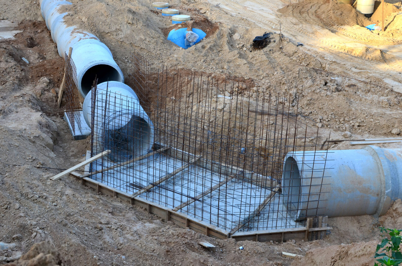 A construction site with pipes and cages in the sand.