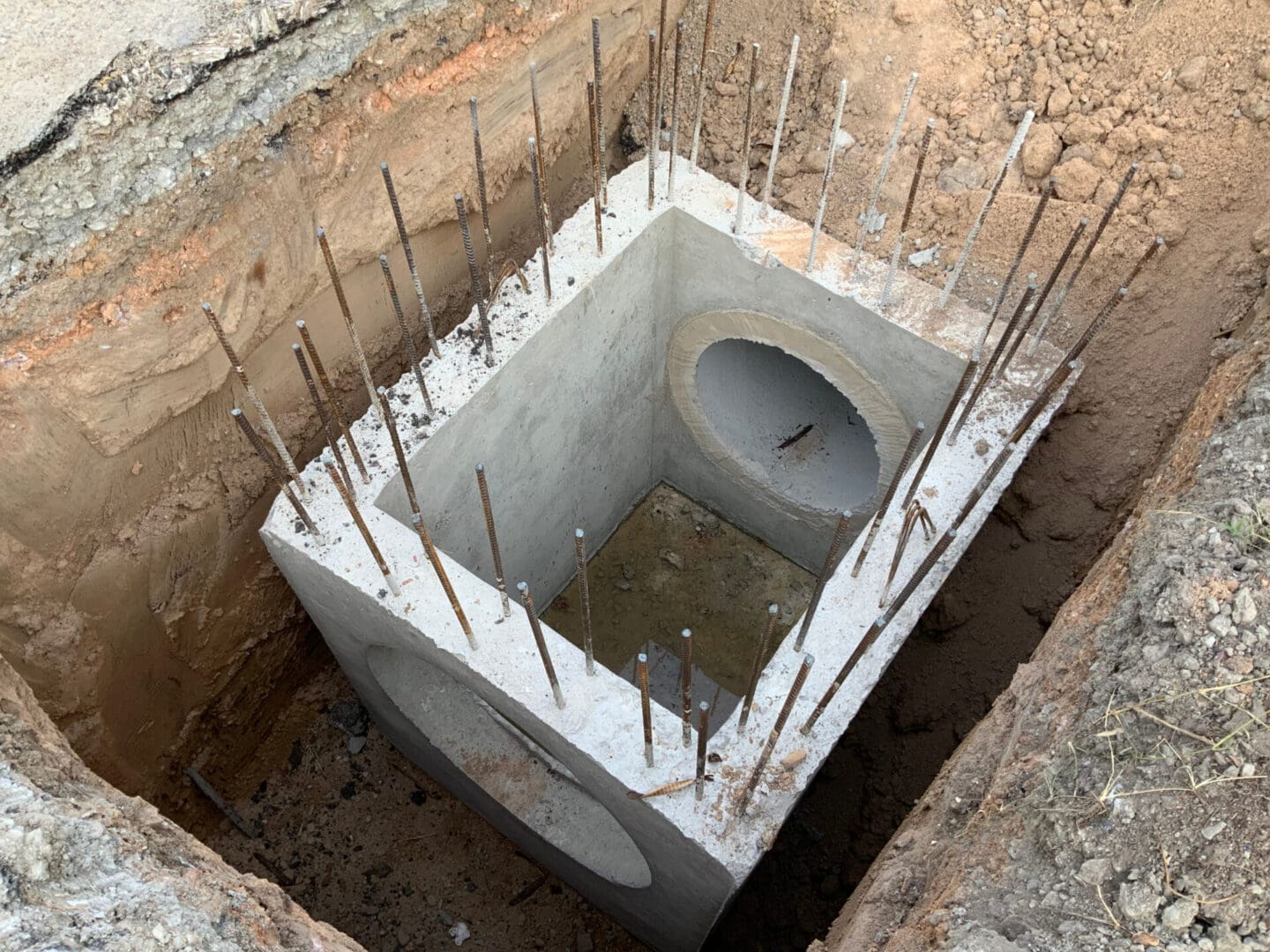 A hole in the ground with holes and nails sticking out of it.