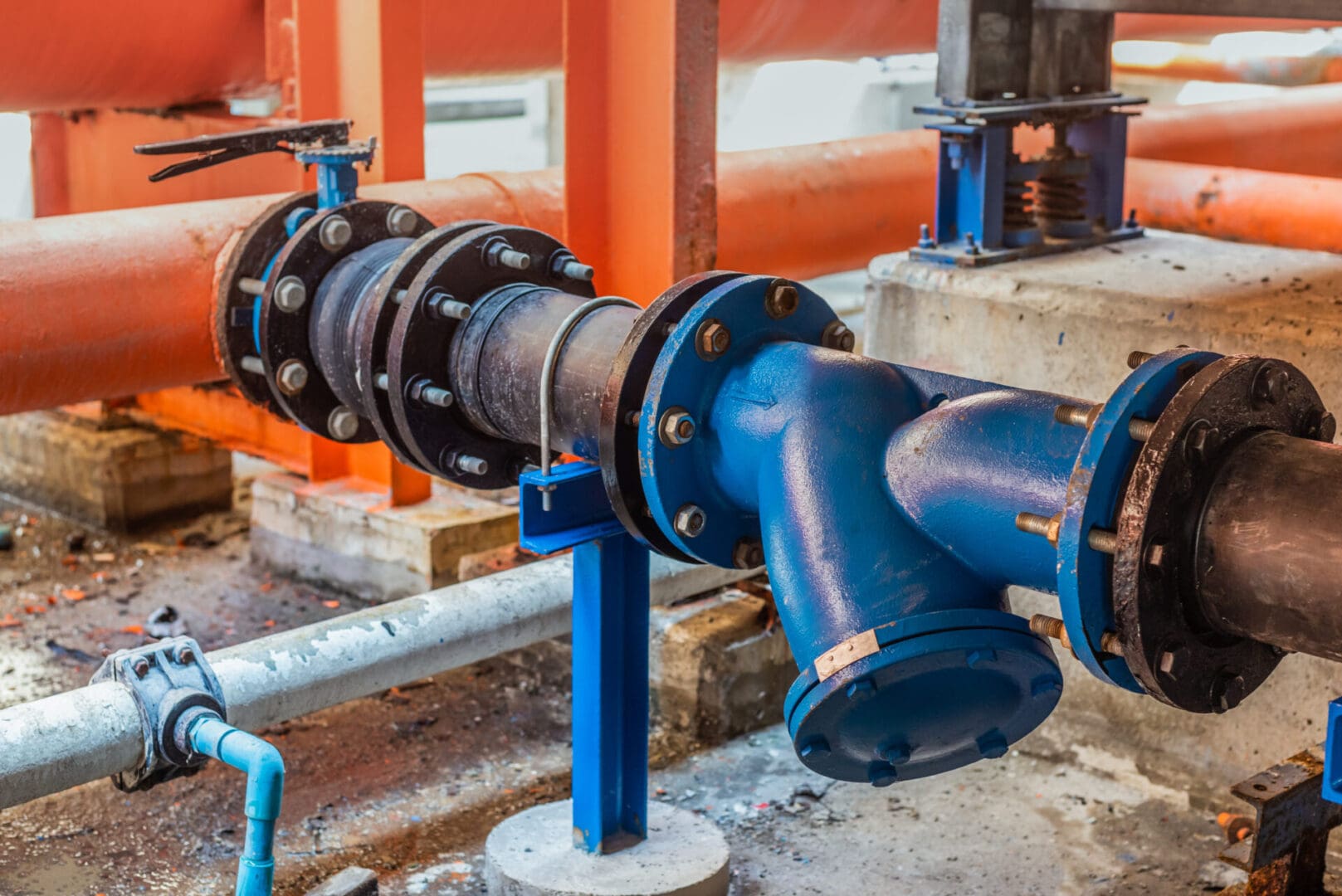 A blue pipe sitting next to pipes and valves.