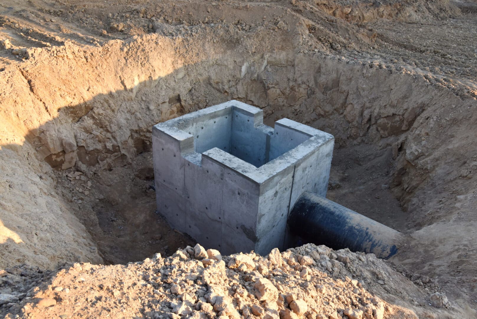 A cement pipe in the middle of a dirt field.