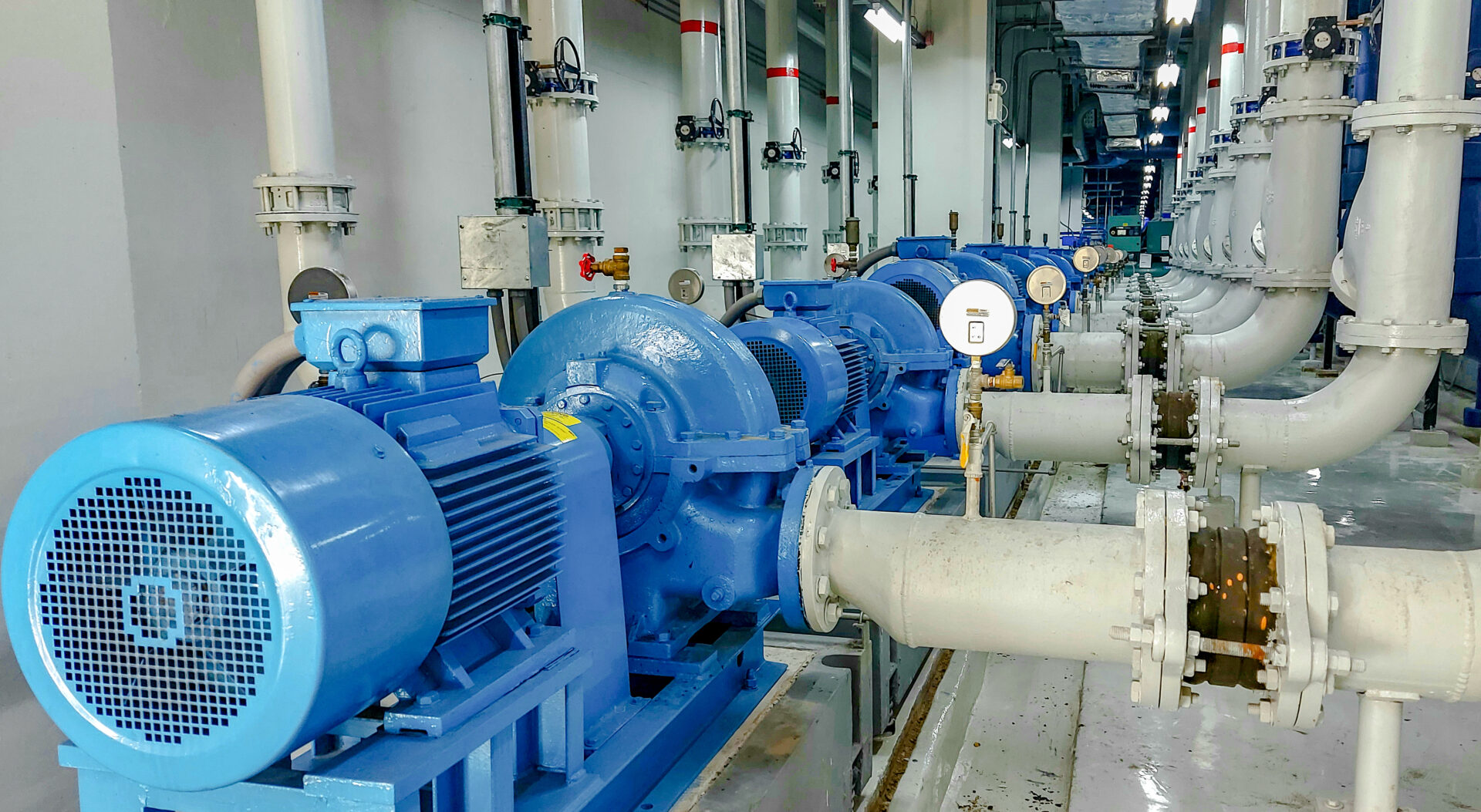 A large industrial machine room with many blue pumps.