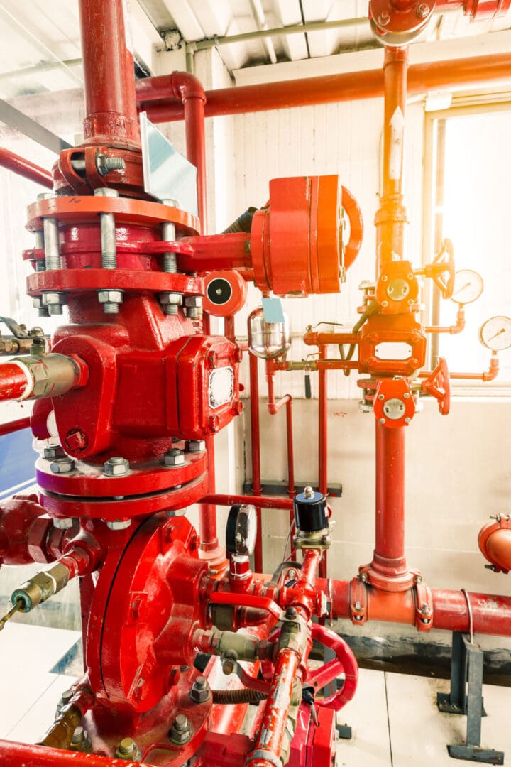 A red fire hydrant and pipes in a room.