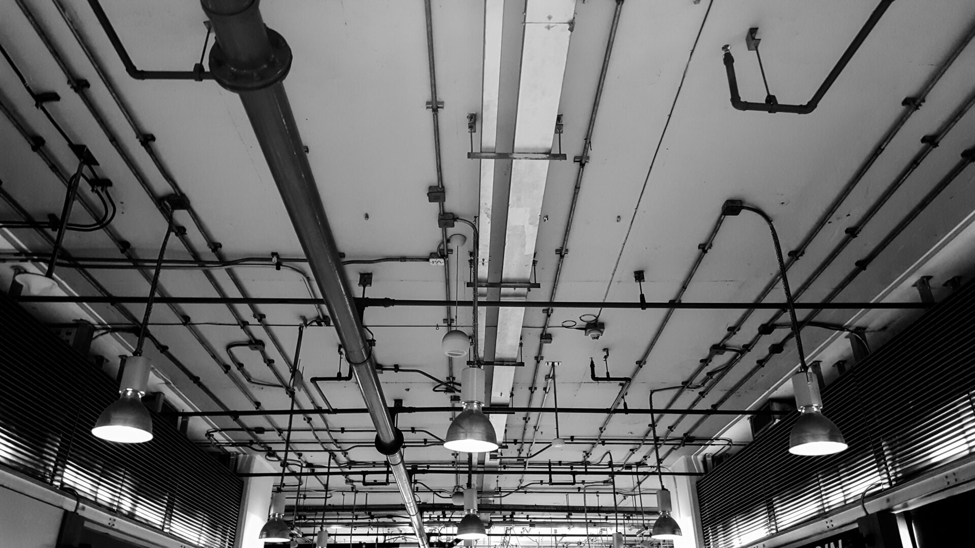 A black and white photo of pipes in an industrial building.