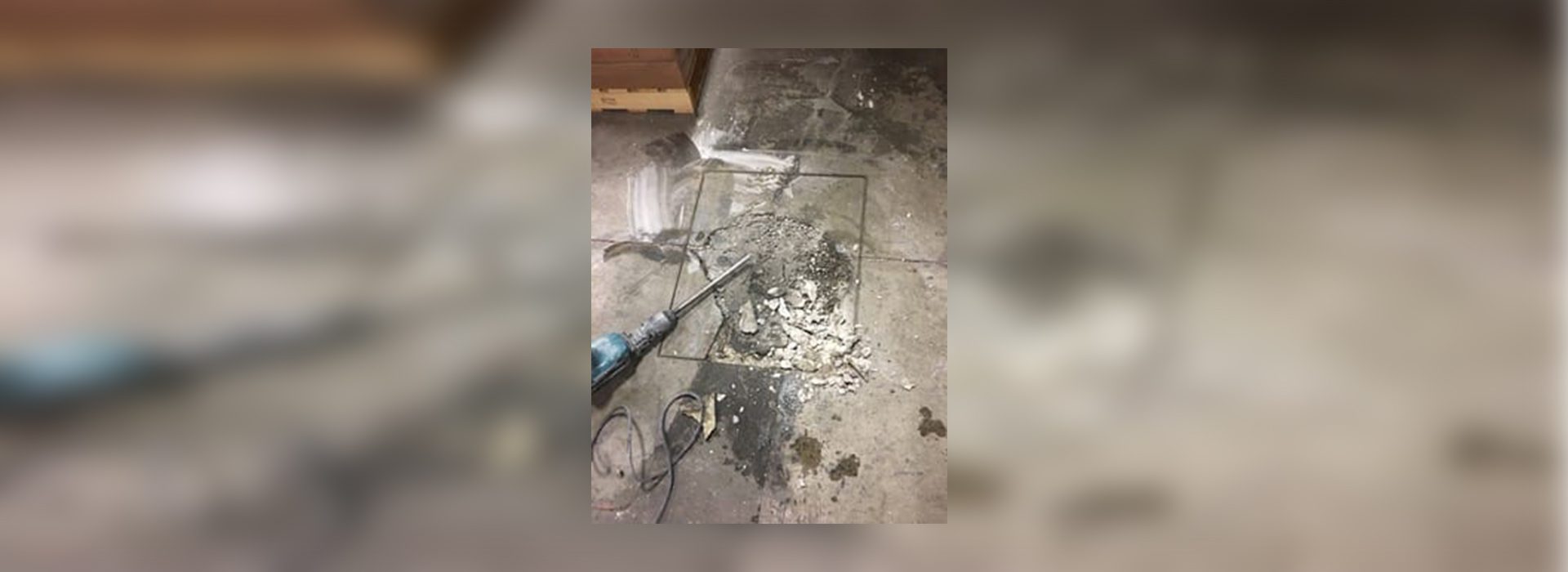 A broken floor with a power drill and some wires