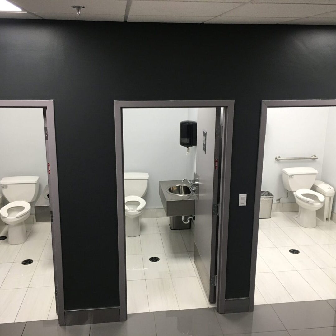 A bathroom with two toilets and three sinks.