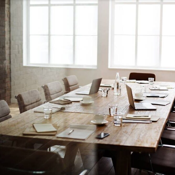 A long wooden table with many empty chairs around it.